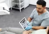 Jak przygotować się do zabiegu implantacji zębów krok po kroku Dentysta pokazuje pacjentce zdjęcie rentgenowskie zębów na tablecie.
