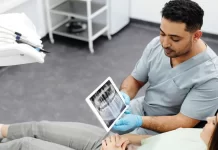 Jak przygotować się do zabiegu implantacji zębów krok po kroku Dentysta pokazuje pacjentce zdjęcie rentgenowskie zębów na tablecie.