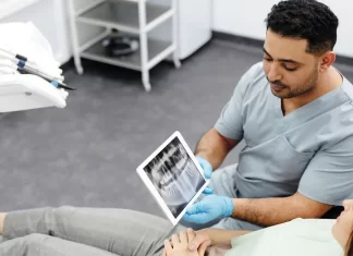 Jak przygotować się do zabiegu implantacji zębów krok po kroku Dentysta pokazuje pacjentce zdjęcie rentgenowskie zębów na tablecie.