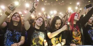 Tłum fanów pod sceną nagrywa koncert smartfonami i unosi ręce.
