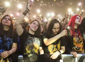 Jak sprawdzić skład i historię zespołu przed koncertem Tłum fanów pod sceną nagrywa koncert smartfonami i unosi ręce.