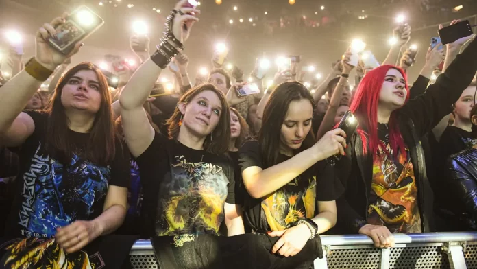 sprawdzanie-skladu-zespolu-przed-koncertem Tłum fanów pod sceną nagrywa koncert smartfonami i unosi ręce.